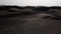 Middle eastern desert, nature landscape. Sand blowing in wind over desert sand dunes in evening desert sunset, sunlight in cinematic slow motion.