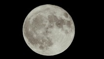 Airplane flying in front of the full moon seen with telescope