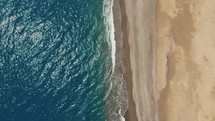Calm ocean near an empty sandy beach coast vertical aerial view