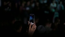 a woman filming a concert on her cellphone 