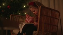 A little girl reading the Bible by the Christmas tree