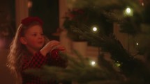 Little Girl Placing an Ornament on the Christmas Tree