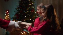 Little sisters receiving gifts from Santa Claus 