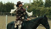 Cowboy holding revolver gun on his black horse