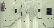 Semiconductor manufacturing facility with workers in clean suits.