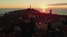 drone flies over medieval town with church at sunset