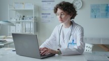 Portrait of Young Female Doctor Working on Laptop in Medical Office
