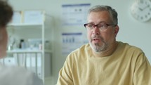 Mid-Aged Patient Having Discussion with Doctor during Medical Appointment
