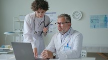 Young Female Doctor Discussing Test Results on Laptop with Senior Colleague
