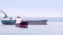 Cargo vessel is moving to the port. Empty ship is going to take cargo or to be fully loaded. One Ship is anchored in anticipation. 2 large cargo tanker for oil, metal, bulk cargo, coal or petrol transportation . Global market leader in the logistics industry. Expertise in international parcel delivery