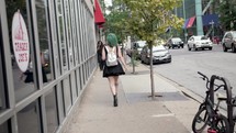 woman with green hair walking down a sidewalk 