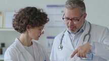 Young Female Doctor Discussing Data on Tablet with Senior Colleague
