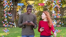 Man and a woman walking and smiling while looking at their phones.