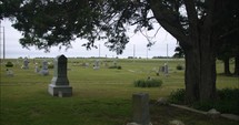 Graveyard tombstones in cemetery on cloudy day.