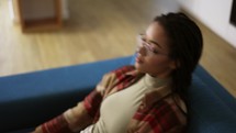 Exhausted African American woman in eyeglasses lay down on sofa.