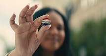 Young woman smiling with an ‘I Voted’ stickers and pin 