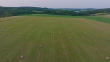 Aerial footage of a large, open field with scattered hay bales