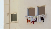 Clothes hanging to dry on a white wall, gently swaying in the breeze - Spain