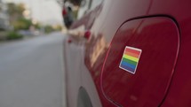 Applying Pride Sticker to Red Car. 