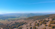 Panorama Of Hills And Mountains With Abundant Autumnal Forest Trees On A Sunny Morning. Aerial Wide