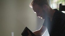 a young man sitting and reading a Bible 