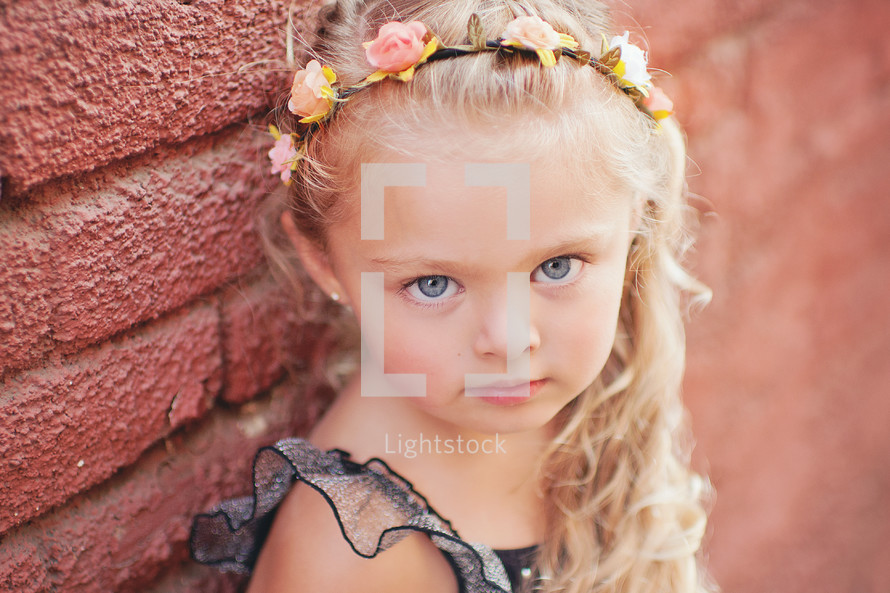 a little girl with a flower headband in her blonde hair 