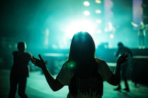 girl with holy holy holy t-shirt with raised hands during a concert 