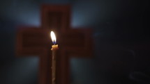Extreme Close-up of Holy Cross with Candle which is blowing out.