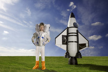 Young caucasian boy dressed as an astronaut standing in front of his rocket themes of imagination dream aspirations - rocket created by the artist