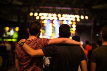 arms around each other at a concert 
