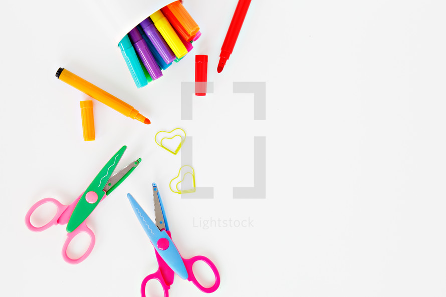 scissors, markers, and paperclips on a white background 