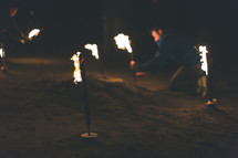 A man planting burning torches into the ground.