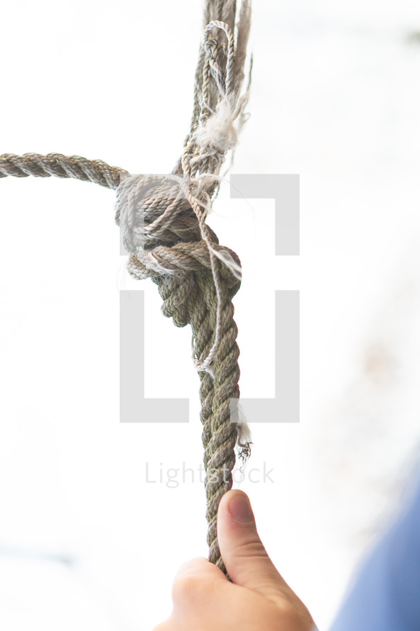 Hand hanging onto rope against white background