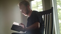 young man sitting reading a Bible 