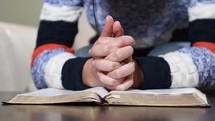 a woman praying over a Bible 