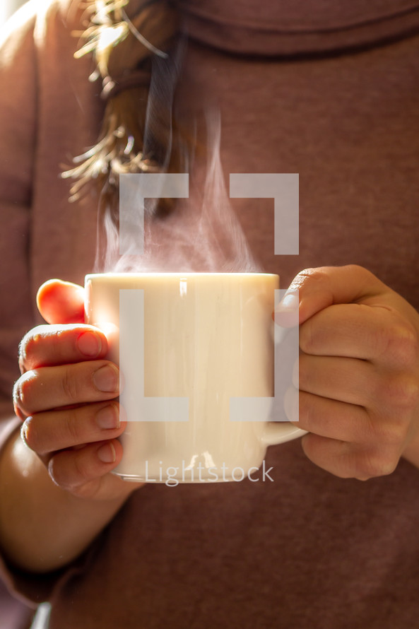 a woman holding a steaming coffee mug 