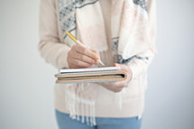 a woman holding a journal and pen 