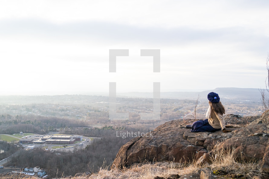 a woman sitting on a mountaintop 
