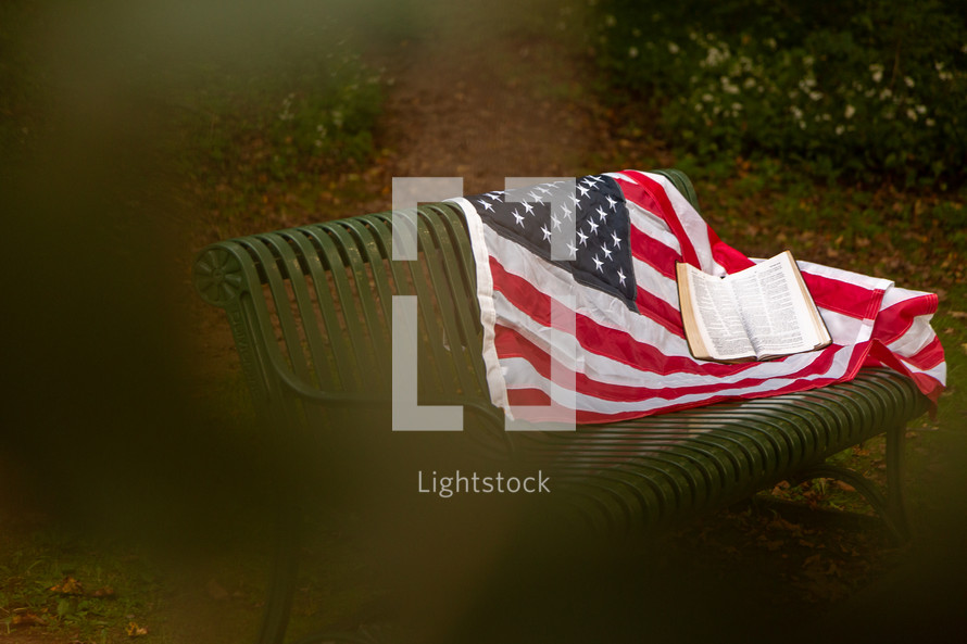 memorial with american flag and Bible on bench
