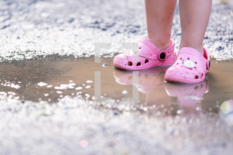 toddler girl standing in a puddle 