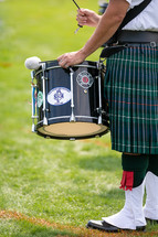 Scottish drummer drumming with grassy background