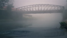 Bridge on river and morning fog.