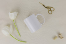 mug, spool, scissors, and white tulips on a white background 