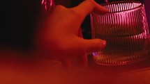 The girl's hand is fondling a cocktail glass with red light
