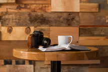 An open Bible, coffee cup, and camera on a round table.