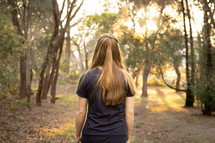 a woman standing alone in a forest 