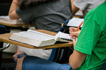 a girl taking notes in Bible study 