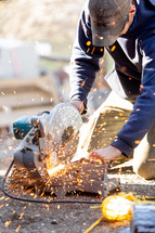 Worker cutting with saw that is creating sparks