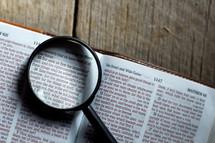 magnifying glass on the pages of a Bible 