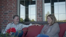 a husband and a wife talking on a porch 
